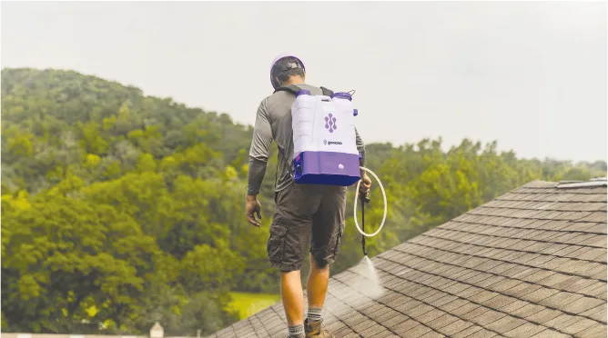 Installer applying the GoNano treatment to an existing shingle roof with a backpack sprayer