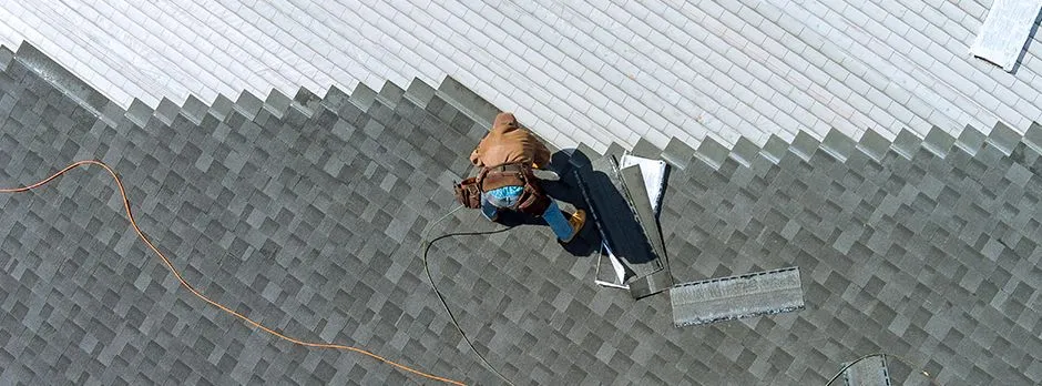 Roofer working from above on a shingle roof